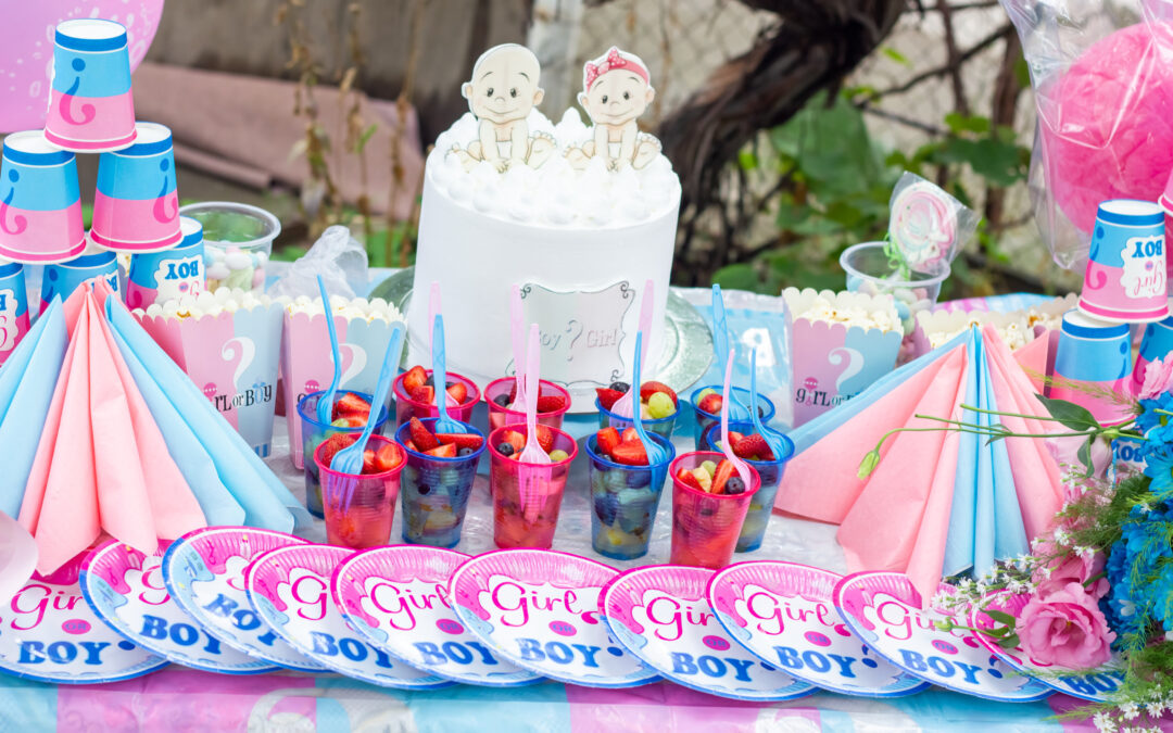 gender reveal party table with cups, plates, and cakes