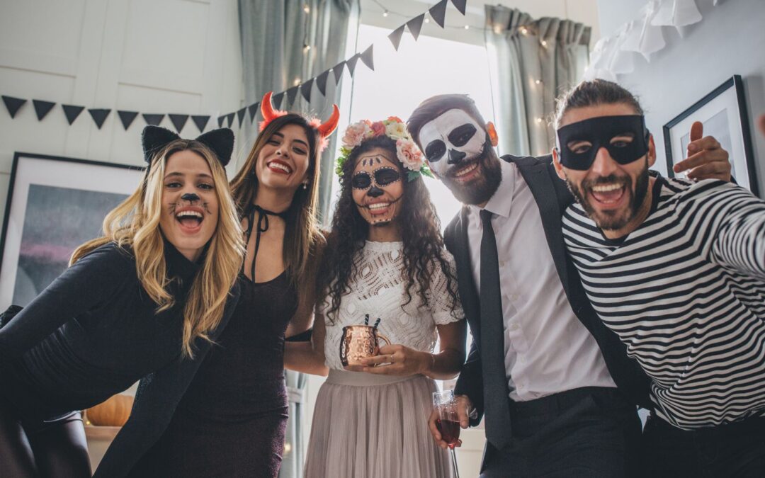 a group of office workers smile at the camera dressed in halloween outfits at one of their annual halloween corporate events