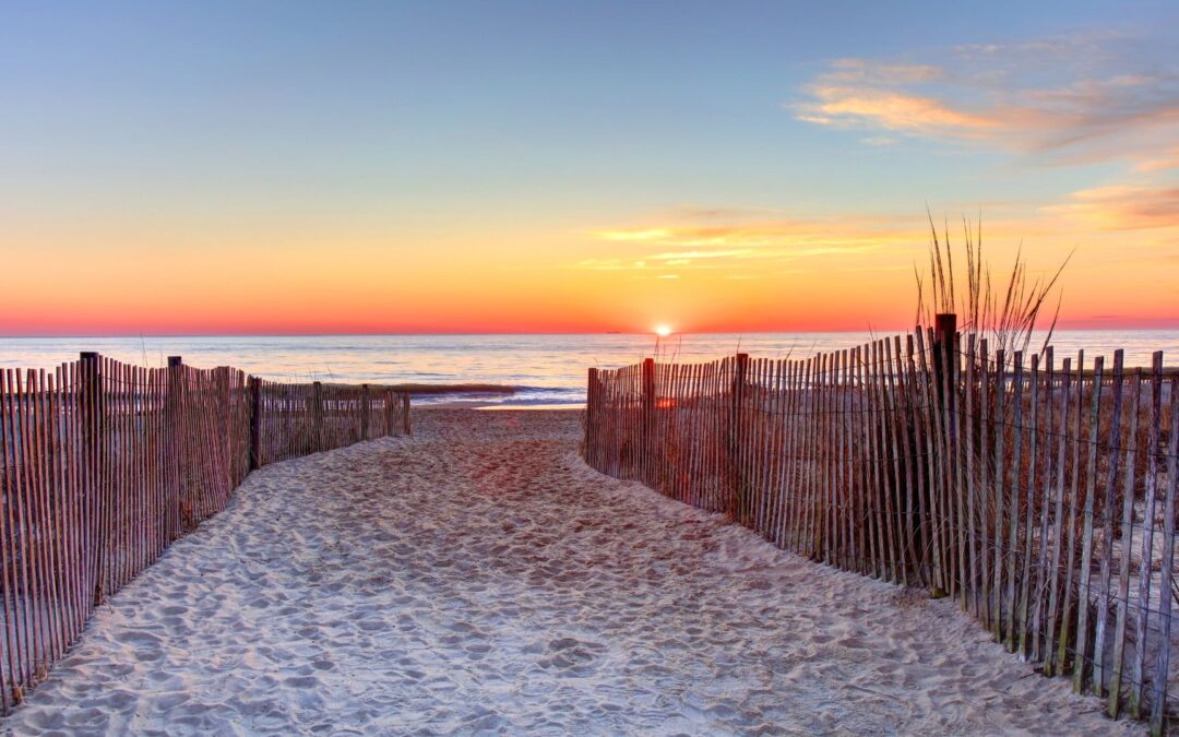 a view of a rehoboth beach delaware sunset casting over the ocean water from a beach view