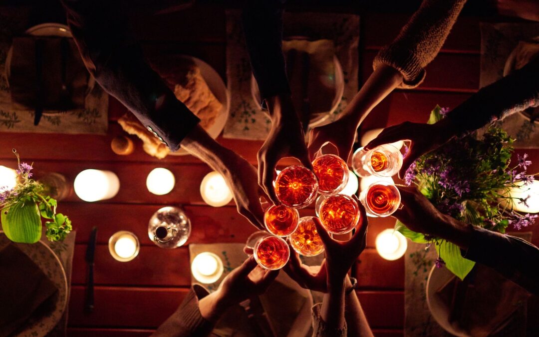 A group of friends toast their drinks at an outdoor night party. Image demonstrates the sort of setting for stargazing.
