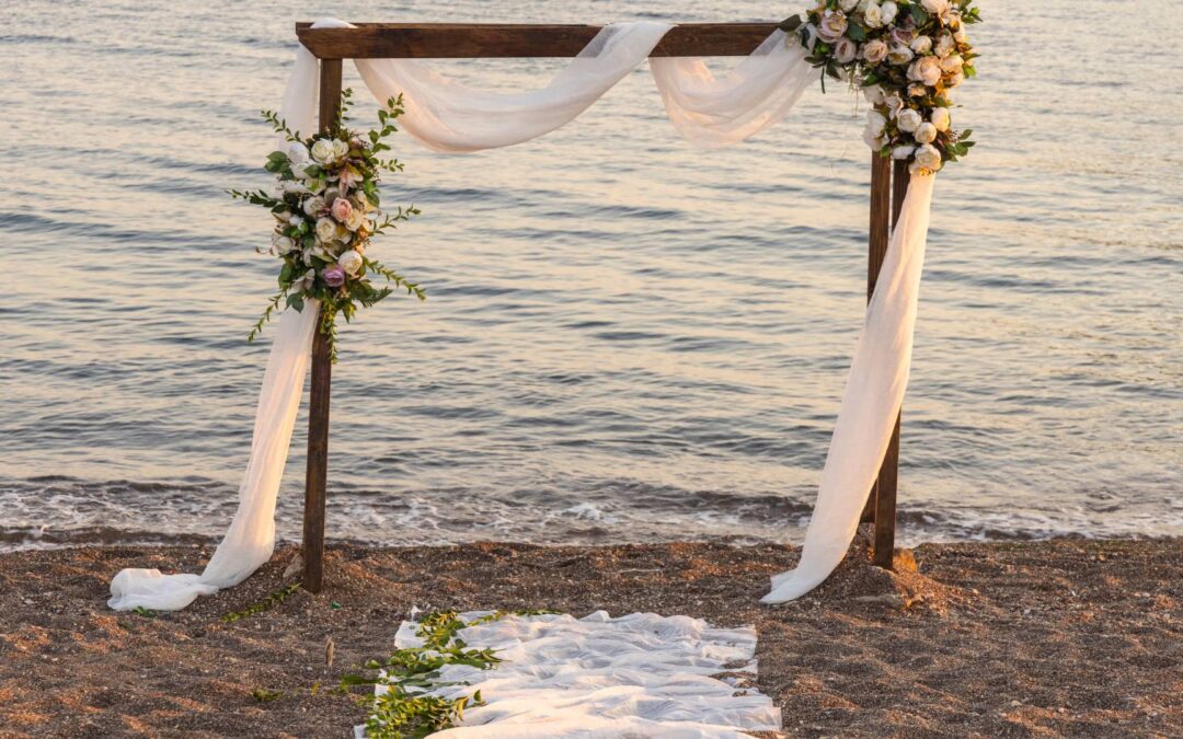A wedding arch is displayed with white sheets at a fall beach wedding.